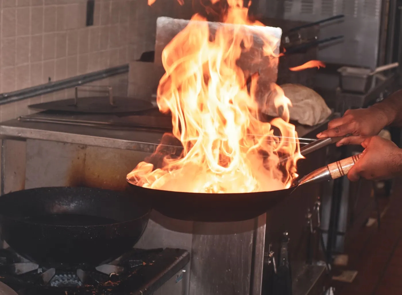 Flames leaping from a wok on a commercial burner